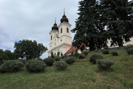 티하니 베네딕트 수도원, 언덕 위로 솟은 두 개의 우아한 흰색 첨탑과 정원의 둥근 관목들이 어우러진 풍경입니다.