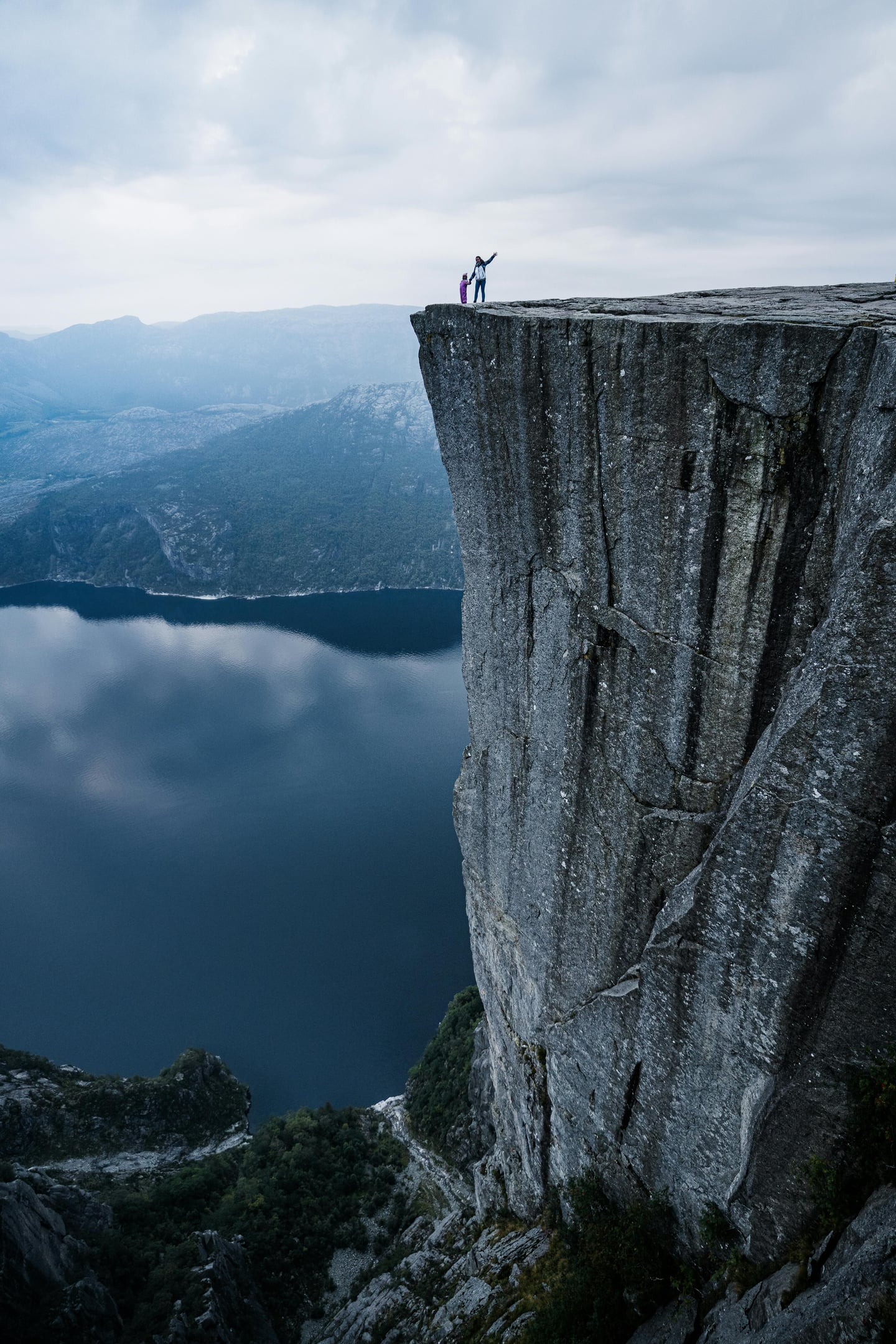 스타방에르 프레이케스톨렌, 아찔한 수직 절벽 끝에서 뤼세피오르의 푸른 절경과 웅장한 산맥을 감상하는 여행자의 모습입니다.