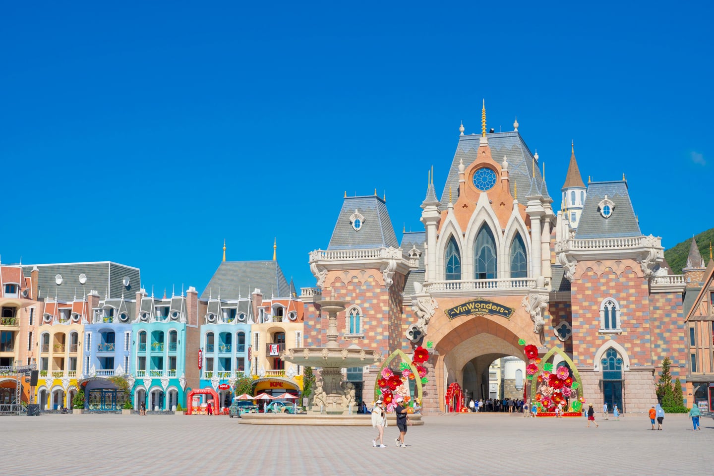 나트랑 빈원더스 무비 캐슬, 푸른 하늘 아래 화려한 유럽풍 성채와 분수대가 어우러진 광장의 이국적인 풍경입니다.