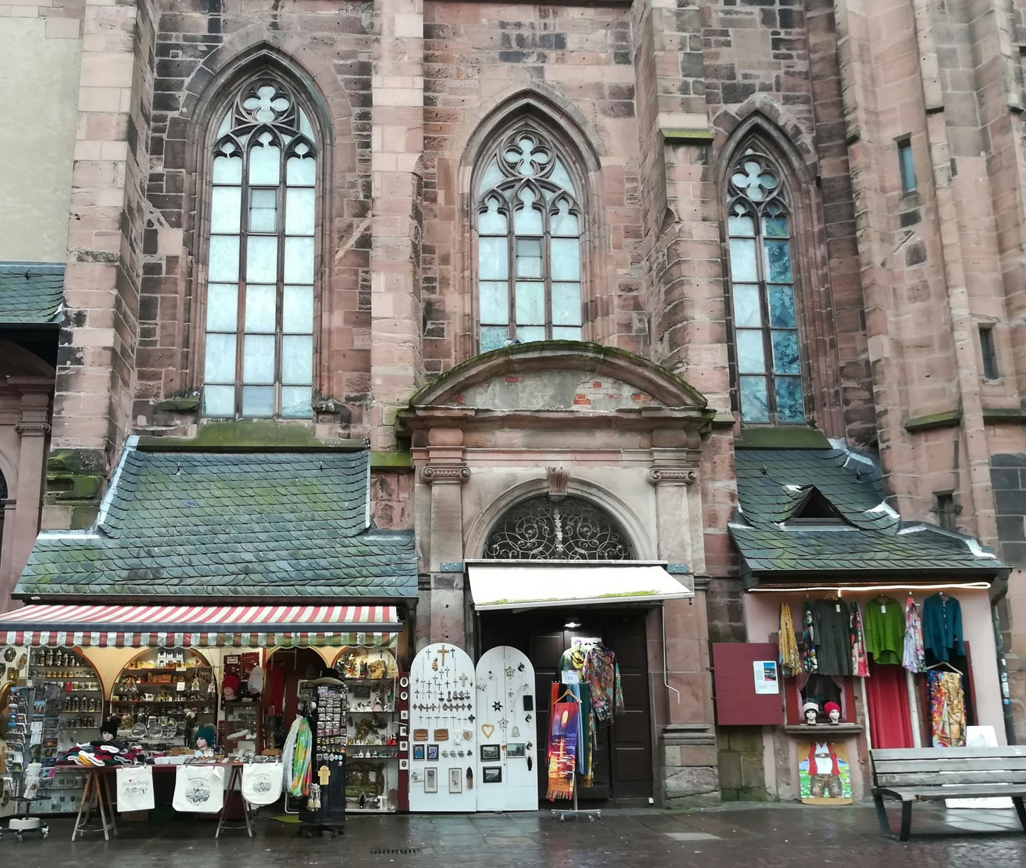 하이델베르크 성령 교회, 고딕 양식의 붉은 사암 외벽 아래 늘어선 아기자기한 기념품 상점과 가판대들의 풍경입니다.