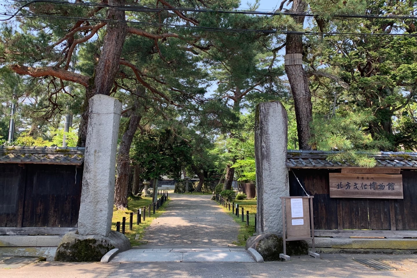 니가타 북방문화 박물관, 거대한 석조 기둥 입구와 울창한 소나무 숲이 어우러진 고즈넉한 박물관 진입로의 풍경입니다.