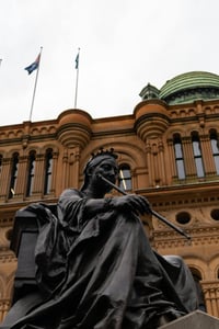 시드니 퀸 빅토리아 빌딩, 웅장한 로마네스크 양식의 건물 외관을 배경으로 당당하게 자리 잡은 빅토리아 여왕 동상의 모습입니다.