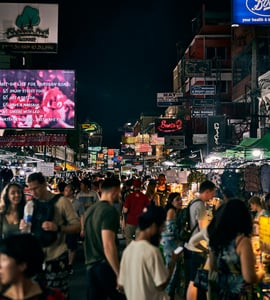 방콕 카오산 로드, 화려한 네온사인 아래 수많은 인파로 북적이는 활기찬 밤거리의 야시장 풍경입니다.