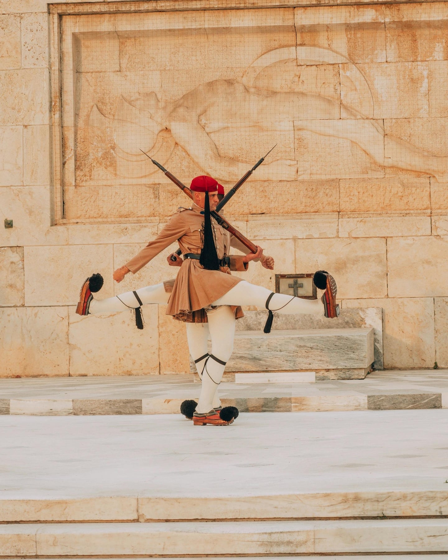 아테네 무명 용사의 묘, 전통 복장을 갖춘 근위병들이 부조 벽면 앞에서 절도 있는 동작으로 교대식을 진행하는 장면입니다.