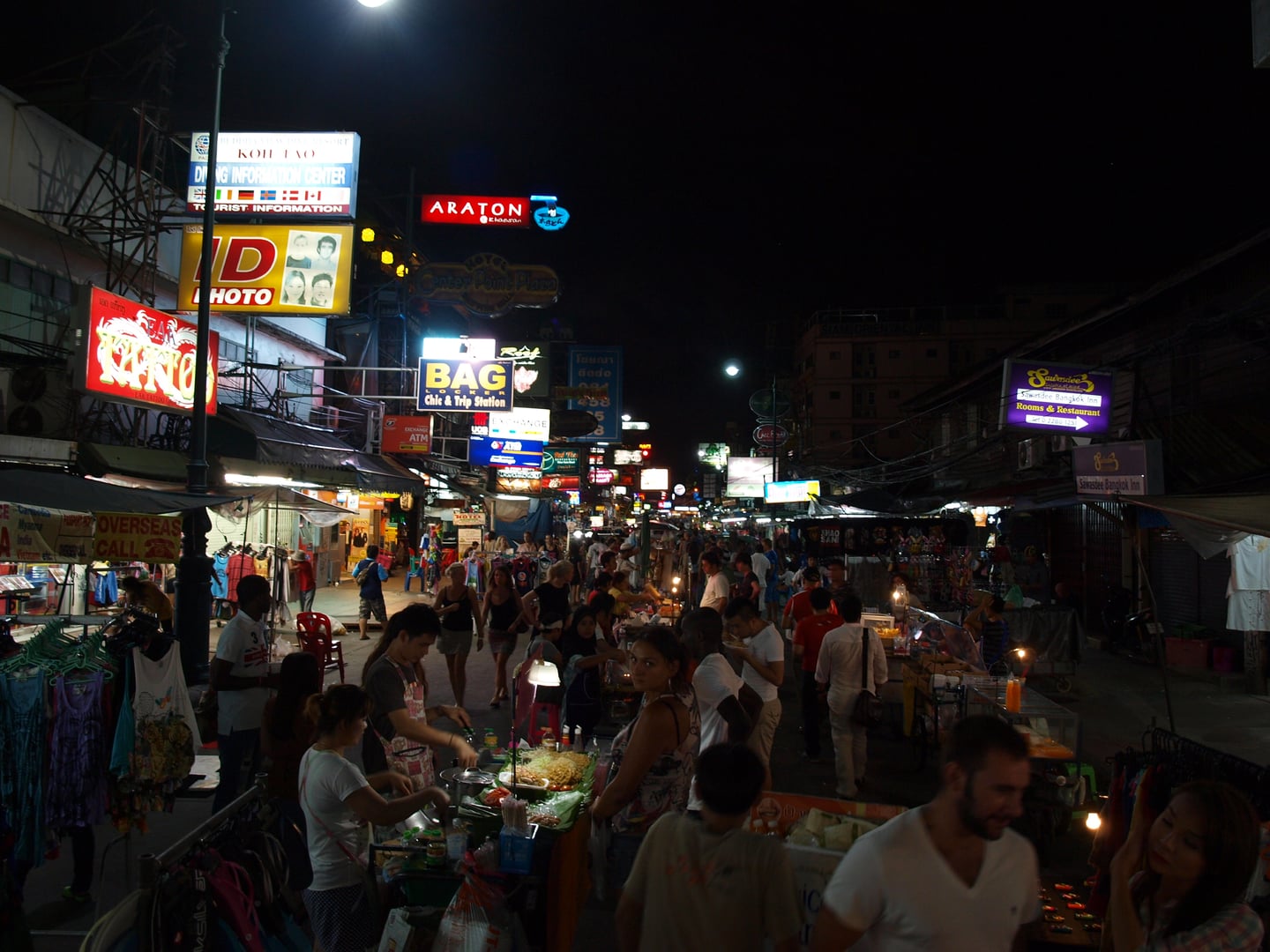 방콕 카오산 로드, 화려한 네온사인 아래 북적이는 인파와 다양한 길거리 음식을 즐기는 관광객들로 가득한 밤거리 풍경입니다.
