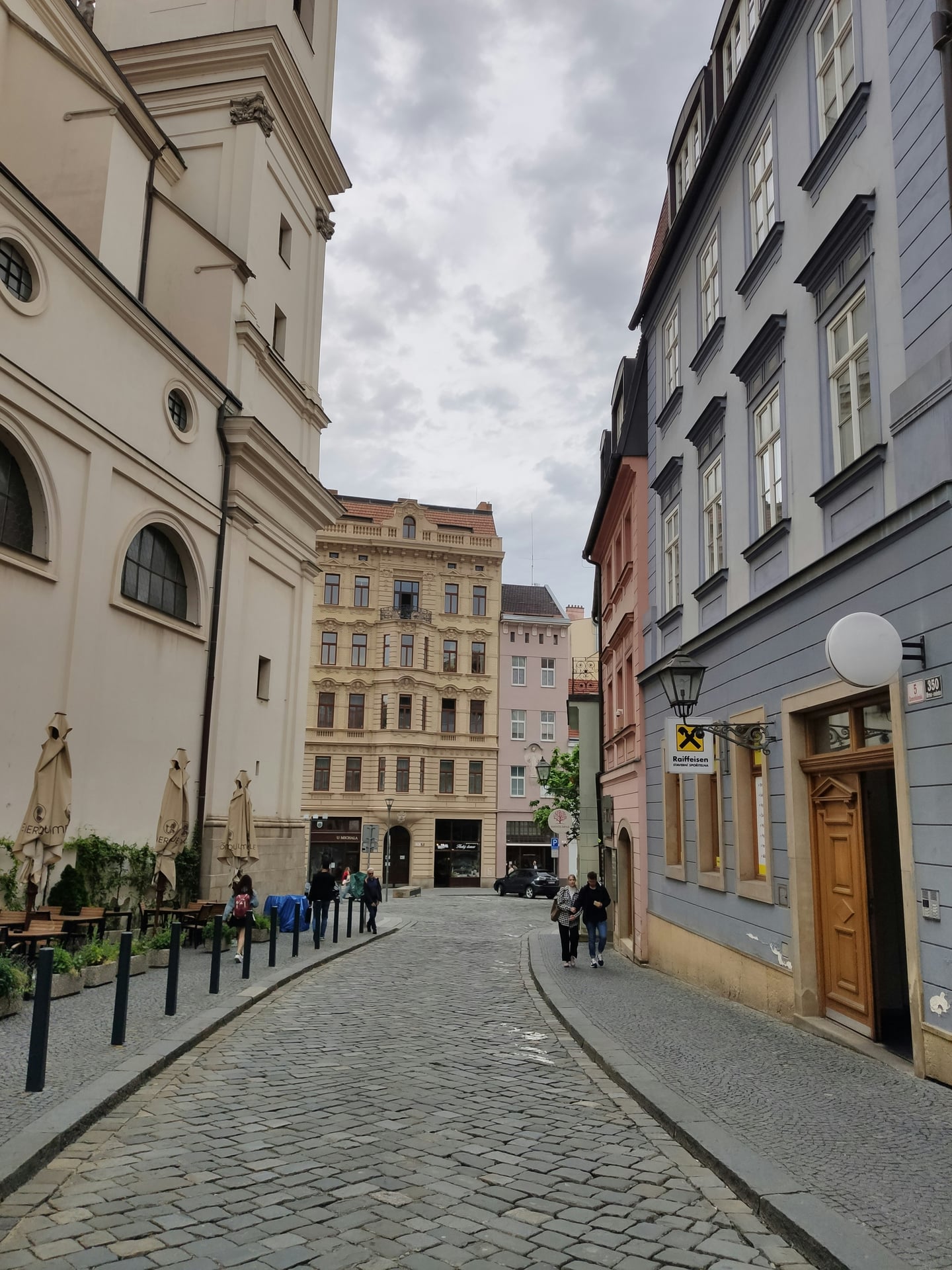 브르노 브르노 구시가지, 고풍스러운 유럽풍 건물들 사이로 펼쳐진 돌길 골목과 여유롭게 산책하는 사람들의 풍경입니다.