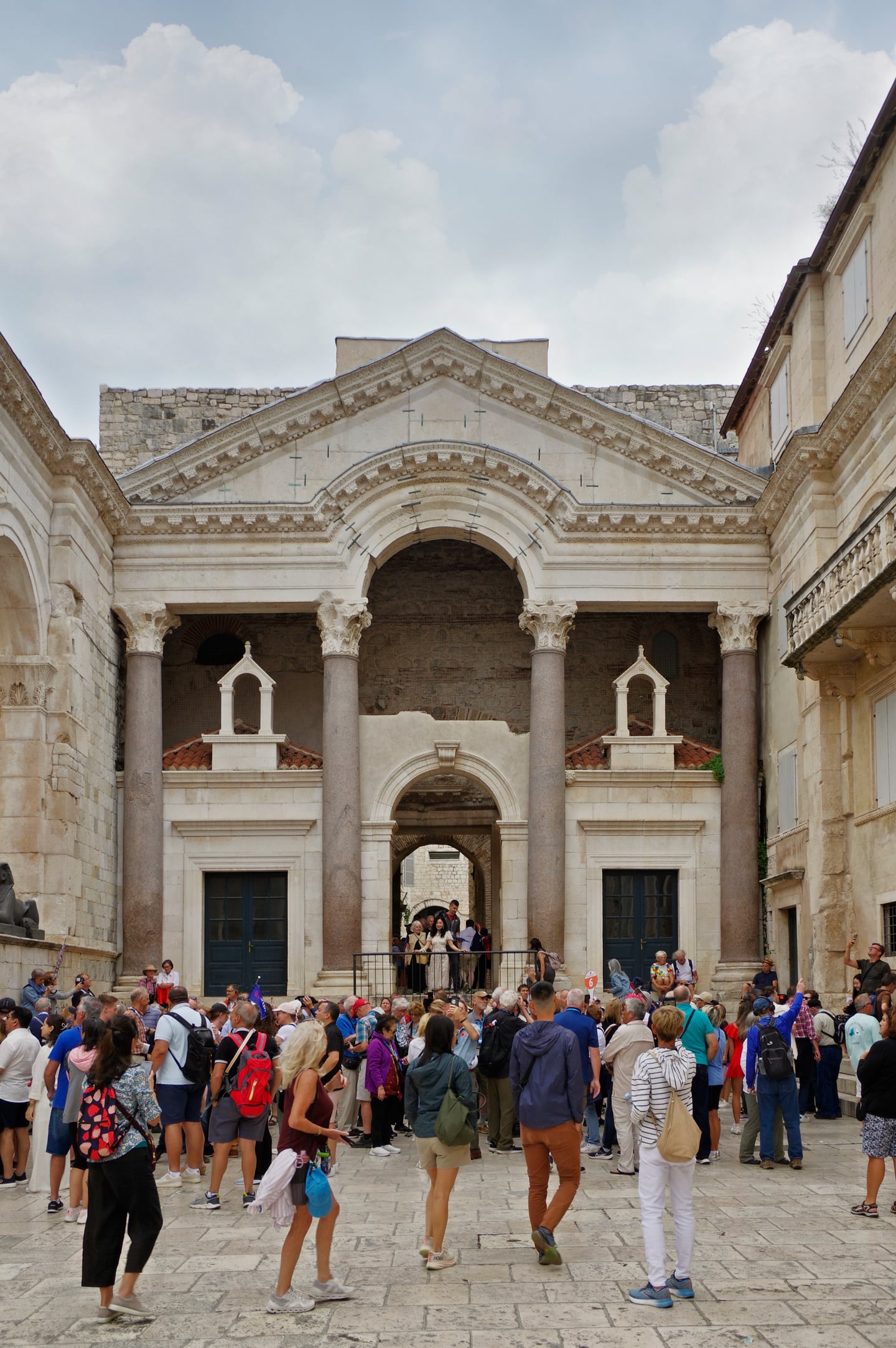 스플리트 디오클레티아누스 궁전, 고대 로마의 웅장한 석조 기둥과 아치형 건축물 아래 광장을 가득 메운 관광객들의 활기찬 모습입니다.