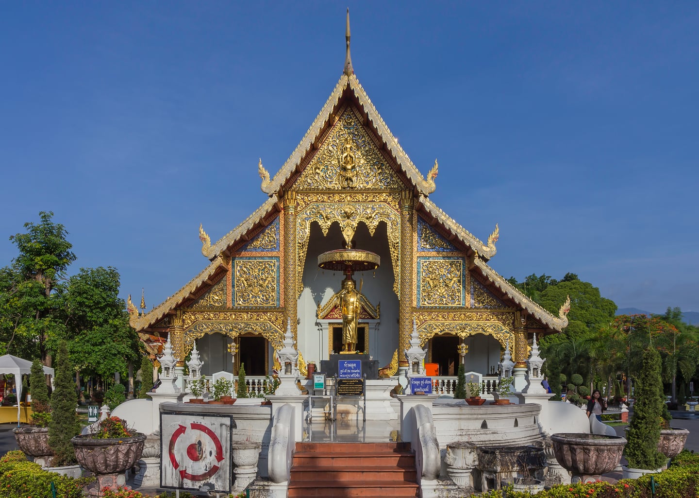 치앙마이 왓 프라싱, 푸른 하늘 아래 정교한 황금빛 조각으로 장식된 란나 양식 사원의 웅장한 정면 모습입니다.