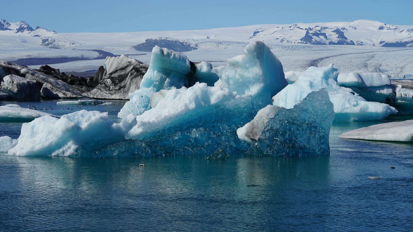 스카프타펠 요쿨살롱 빙하 라군, 맑고 푸른 호수 위에 떠 있는 거대한 청백색 빙산들과 멀리 보이는 설산의 웅장한 풍경입니다.