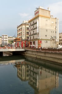 나가사키 나가사키 차이나타운, 수로에 반사된 화려한 중국식 건물들과 붉은색 입구 장식이 어우러진 이국적인 풍경입니다.