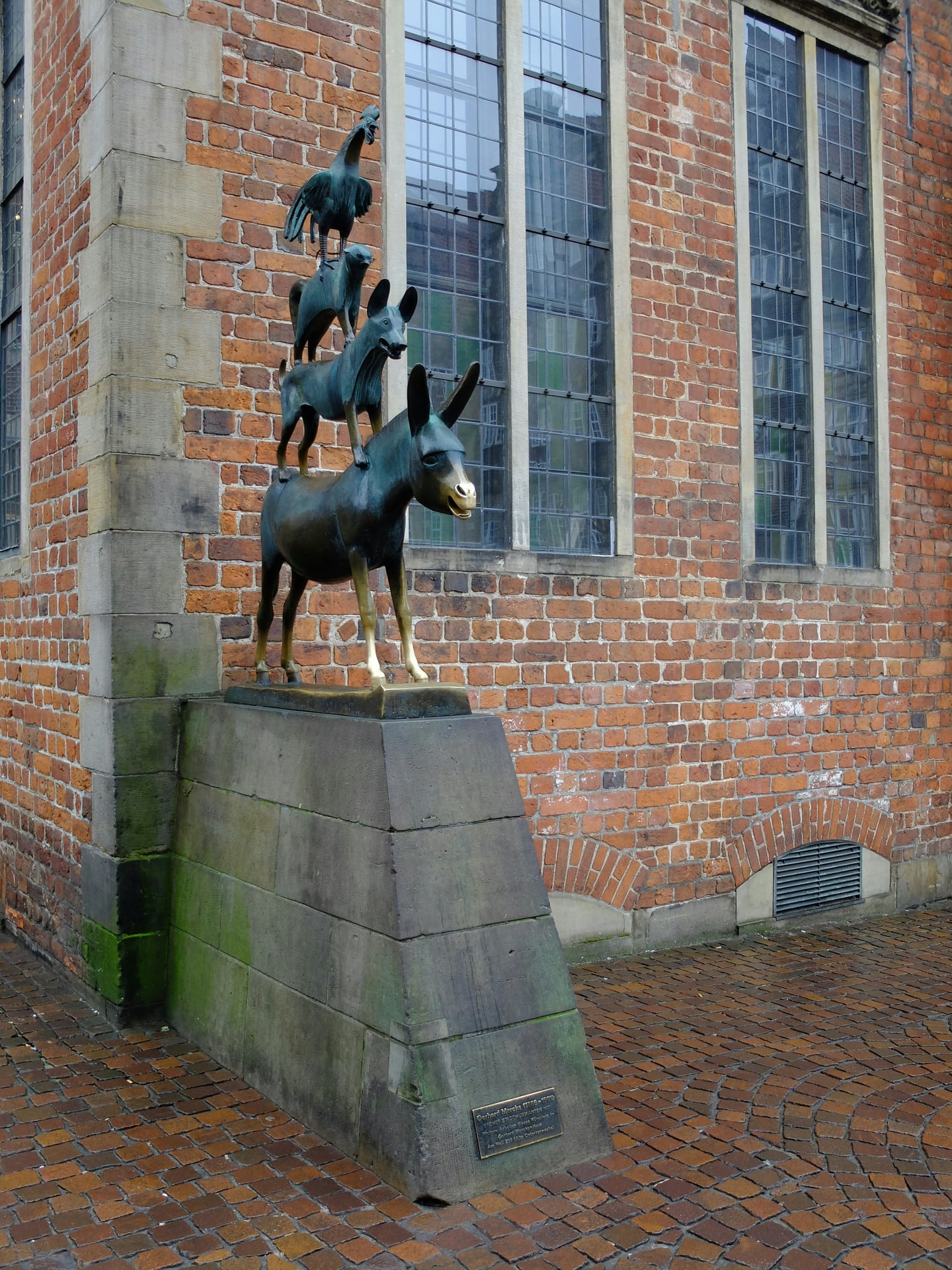 브레멘 브레멘 음악대, 붉은 벽돌 시청사 벽면을 배경으로 당나귀와 동물들이 층층이 쌓인 유명한 청동 조각상의 모습입니다.