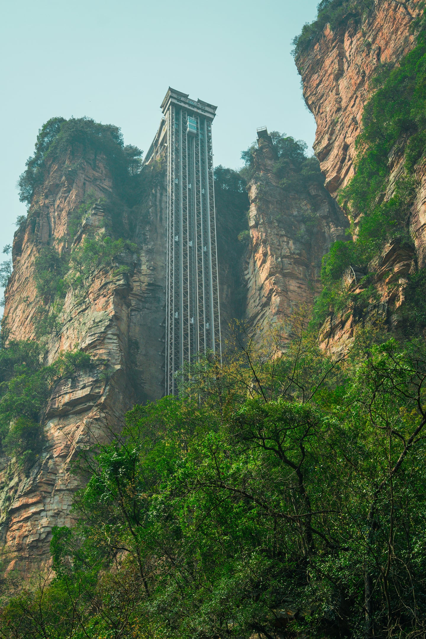 장가계 백룡 엘리베이터, 거대한 수직 암벽을 따라 설치된 세계 최고 높이의 야외 엘리베이터와 웅장한 자연 경관이 어우러진 모습입니다.