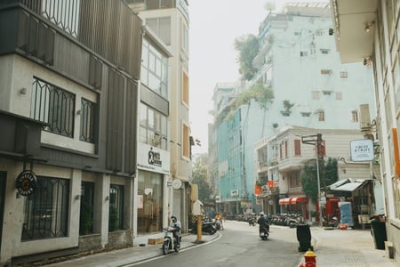 호치민 호치민 카페 빌딩, 세련된 카페 건물들이 늘어선 거리 사이로 오토바이가 지나가는 활기찬 베트남 도심의 일상 풍경입니다.