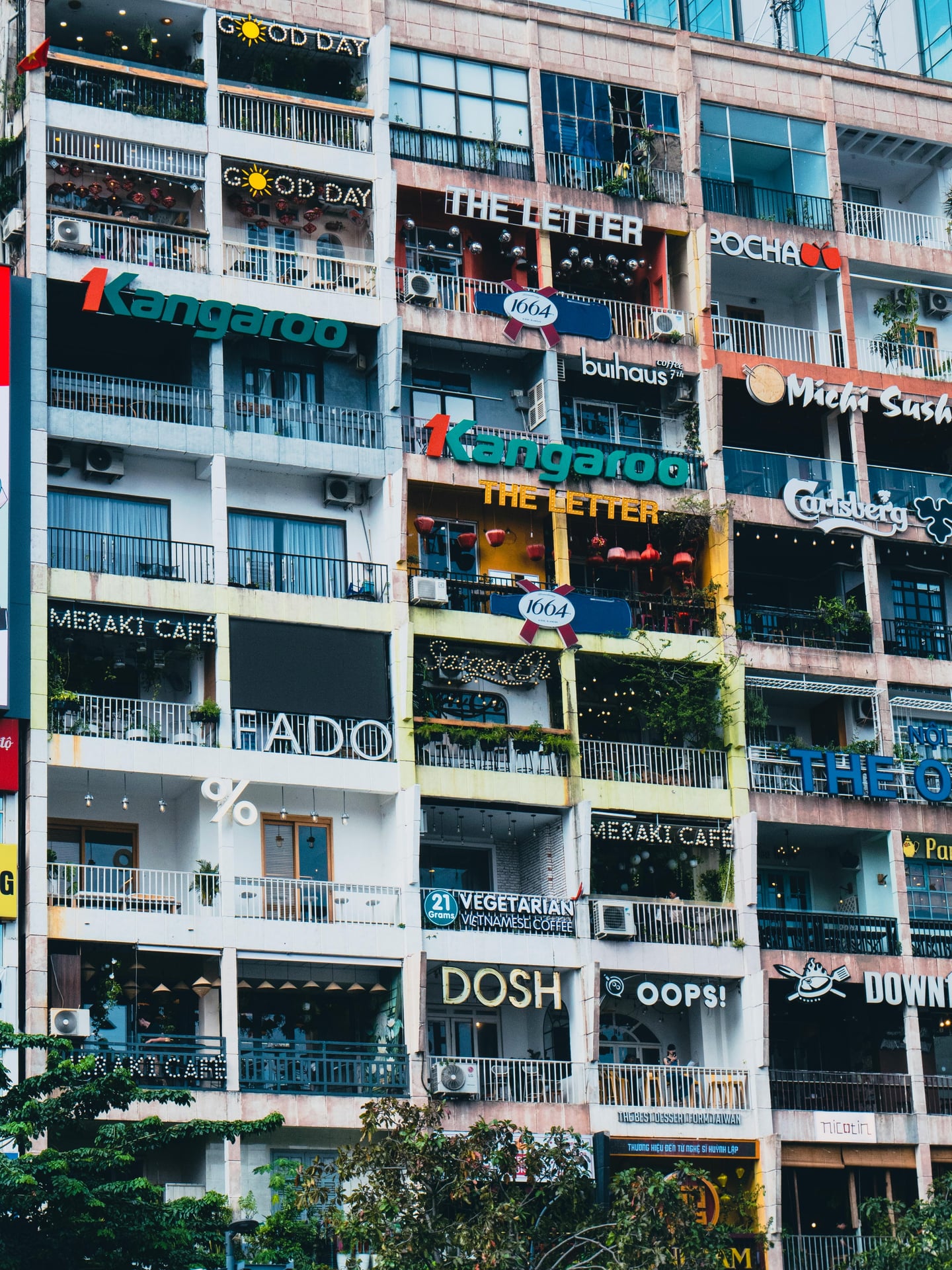 호치민 더 카페 아파트먼트, 격자무늬 아파트 외벽을 가득 채운 다채로운 카페 간판과 테라스가 자아내는 이국적인 도시 풍경입니다.