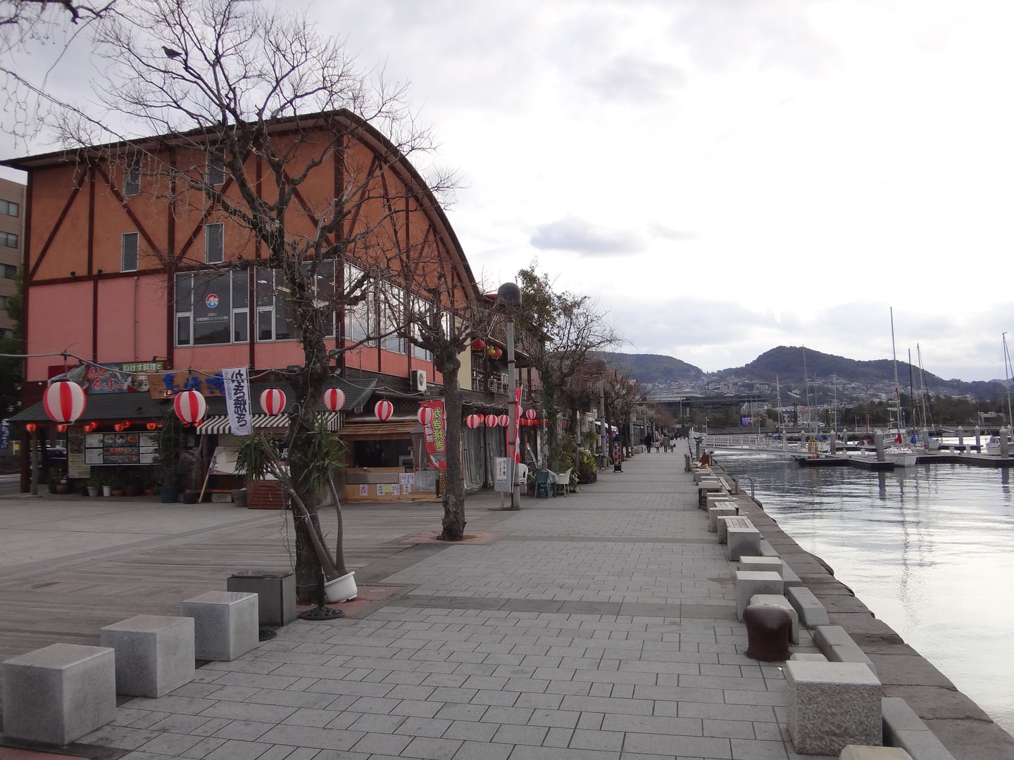 나가사키 데지마 워프, 바다를 따라 늘어선 상점가와 요트가 정박한 항구의 평화로운 산책로 풍경입니다.