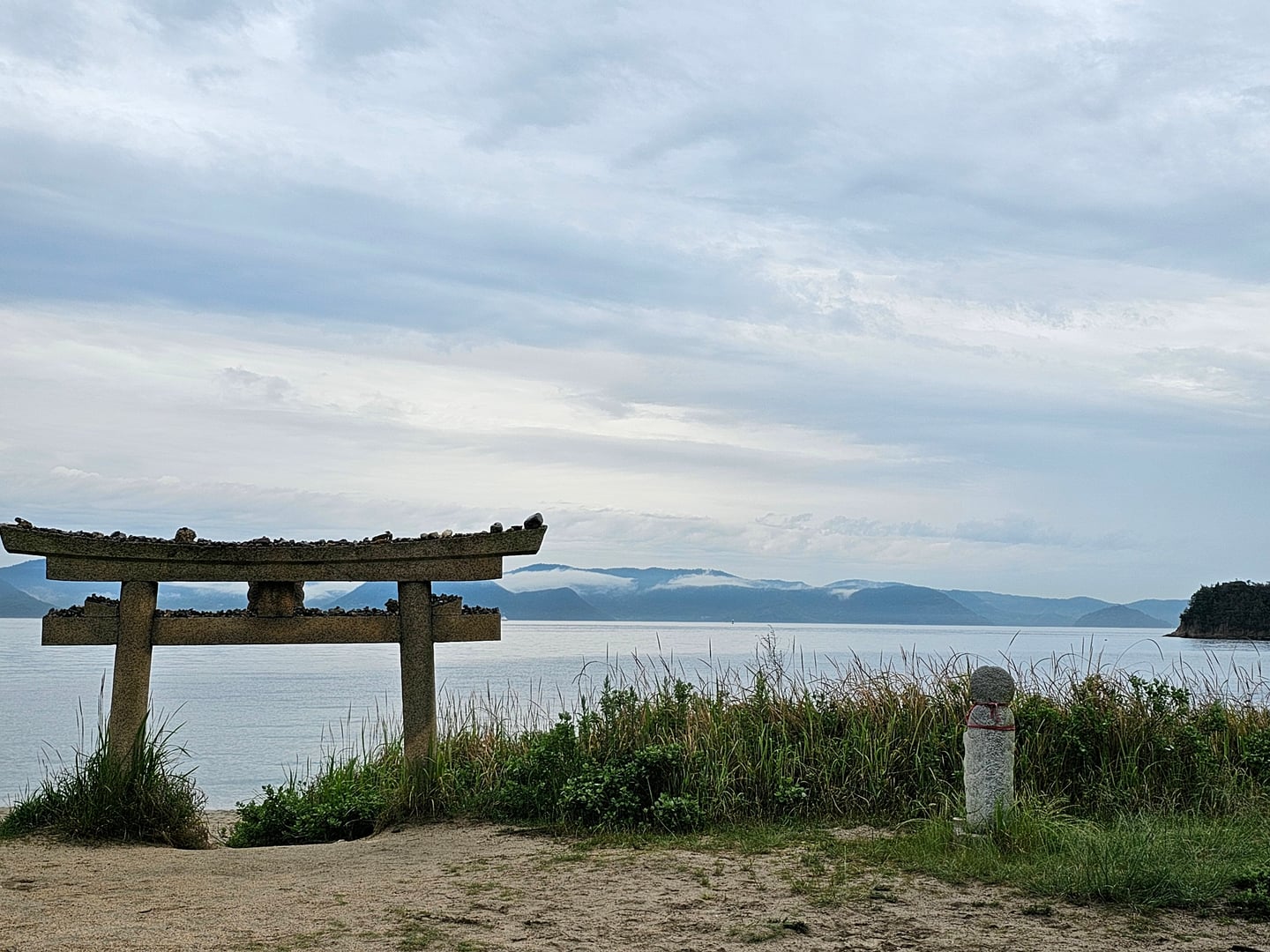 나오시마 나오시마 섬, 바다를 배경으로 해변에 서 있는 석조 토리이와 그 위에 쌓인 작은 돌들.