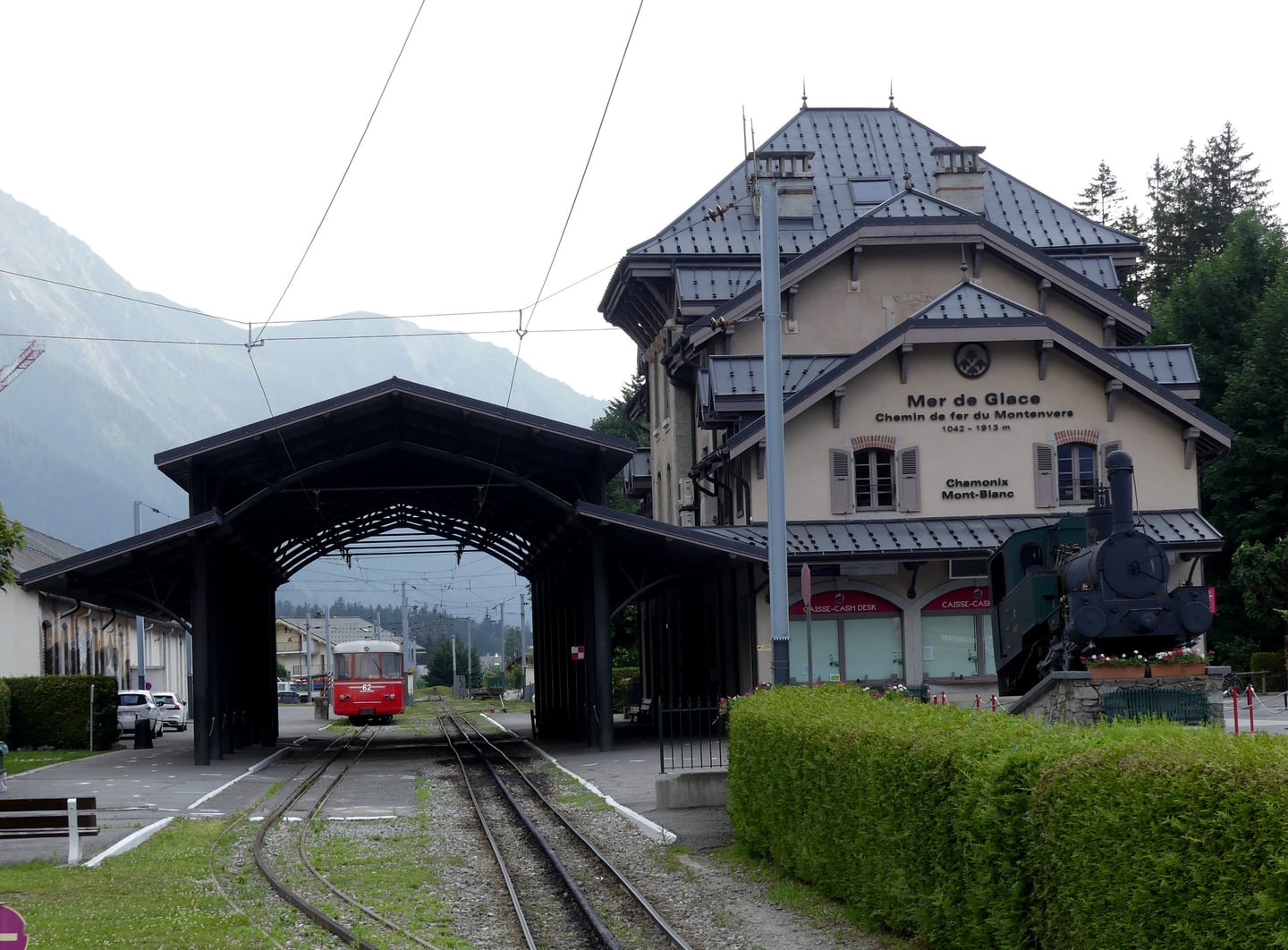 샤모니 몽땅베르, 고풍스러운 산악 열차 역사와 선로 위를 달리는 붉은색 열차가 어우러진 알프스의 평화로운 풍경입니다.