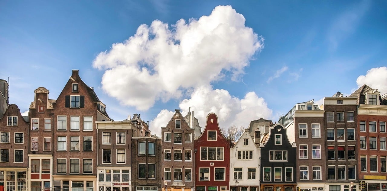 암스테르담 암스테르담 시내, 푸른 하늘 아래 다채로운 색상의 전통적인 박공지붕 건물들이 조화롭게 늘어선 도심 전경입니다.