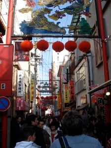 나가사키 나가사키 차이나타운, 붉은 등불과 화려한 용 장식이 어우러진 활기찬 거리 풍경과 붐비는 관광객들의 모습입니다.