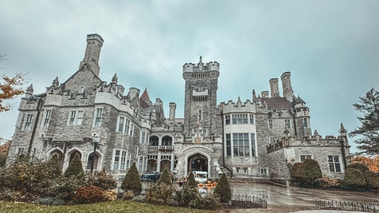 토론토 카사 로마, 흐린 날씨 속에서 웅장함을 드러내는 고딕 양식의 석조 성벽과 화려한 건축미가 돋보이는 전경입니다.