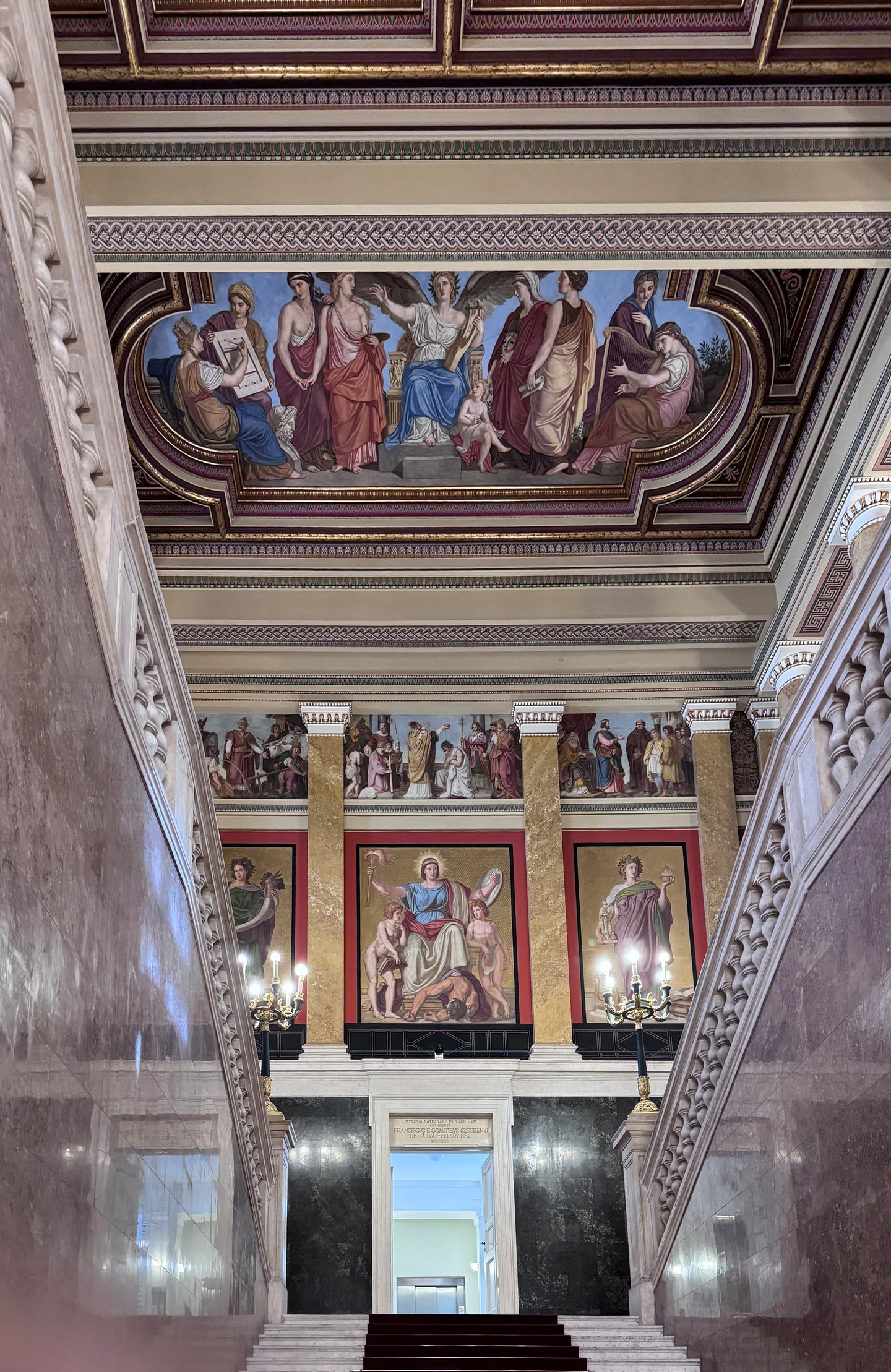 부다페스트 국립박물관, 화려한 천장 벽화와 정교한 프레스코화가 어우러진 웅장한 대리석 계단실의 내부 전경입니다.