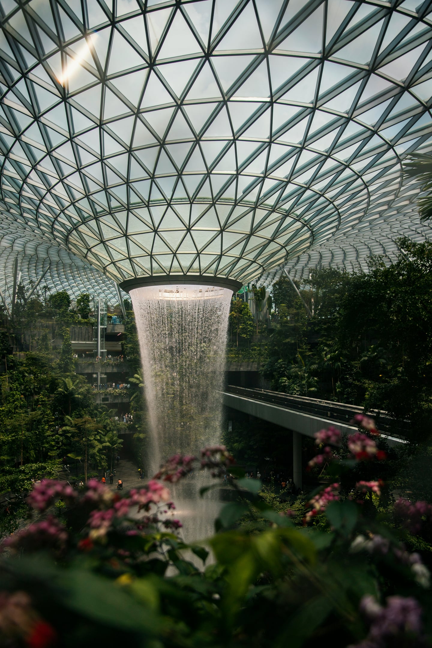 싱가포르 쥬얼 창이, 기하학적인 유리 돔 천장에서 쏟아지는 거대한 실내 폭포와 푸른 정원이 어우러진 웅장한 풍경입니다.