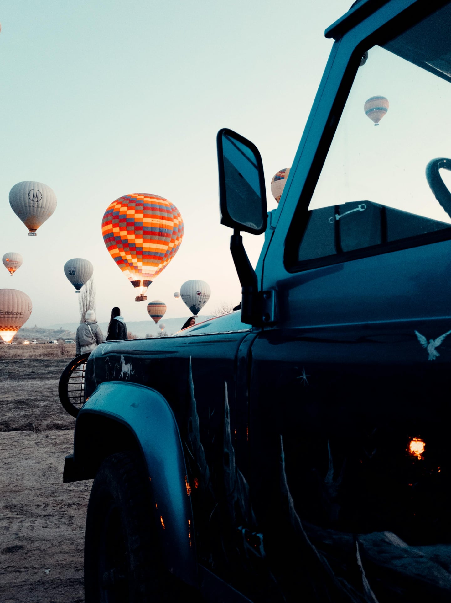 카파도키아 지프 사파리, 새벽녘 광활한 대지 위로 화려한 열기구들이 떠오르는 환상적인 풍경을 지프 차량 옆에서 바라본 모습입니다.