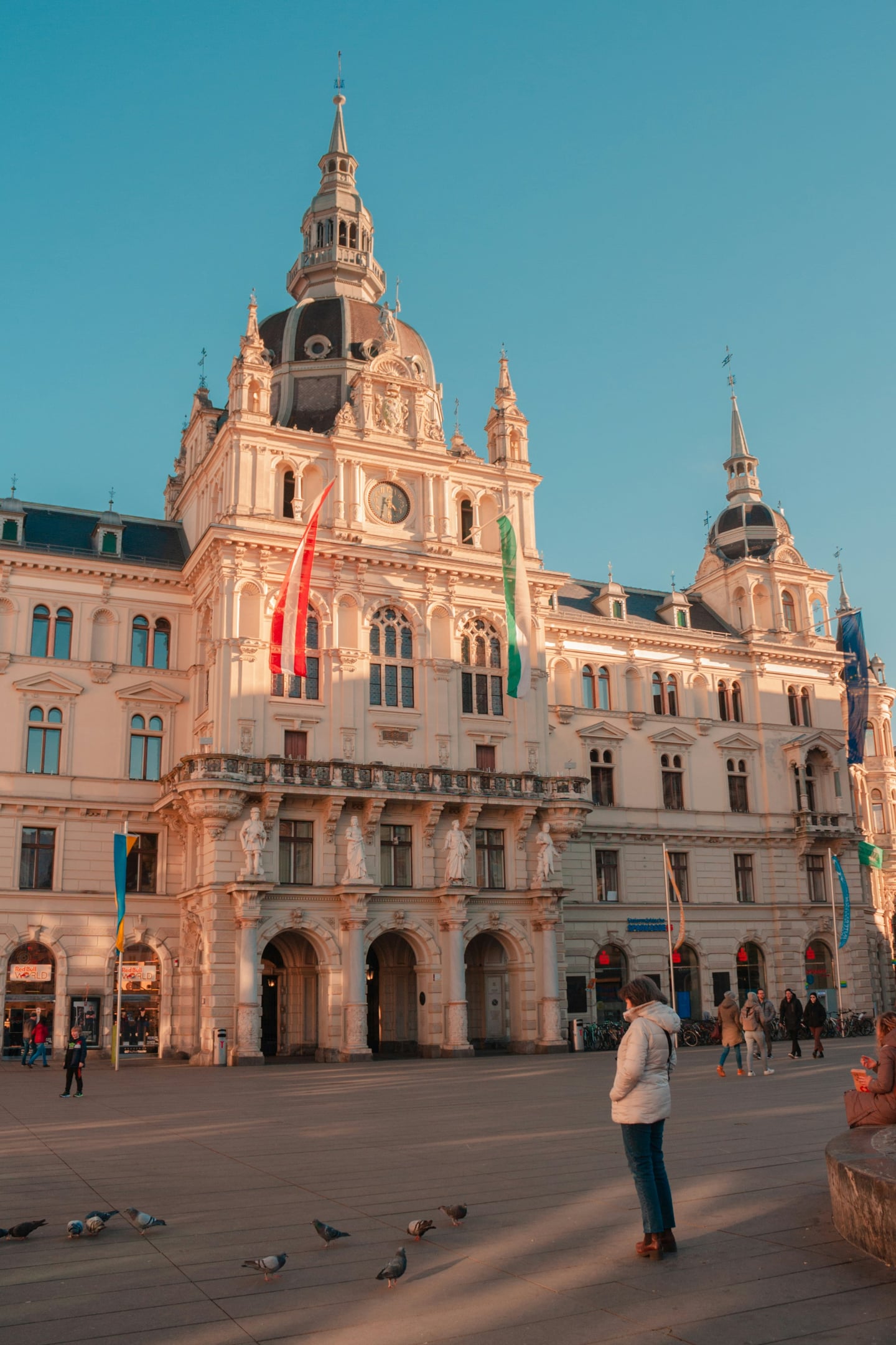 그라츠 그라츠 구시가지, 따뜻한 오후 햇살 아래 웅장하게 서 있는 르네상스 양식의 시청사와 활기찬 중앙 광장의 풍경입니다.