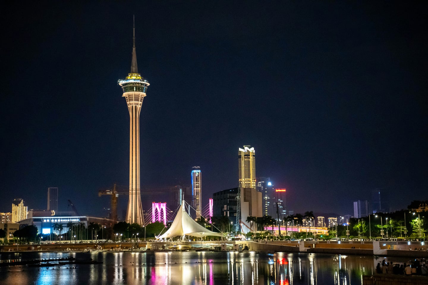 마카오 마카오 타워, 칠흑 같은 밤하늘을 배경으로 화려한 조명을 밝힌 타워와 수면에 비친 도심의 야경이 환상적인 조화를 이룹니다.