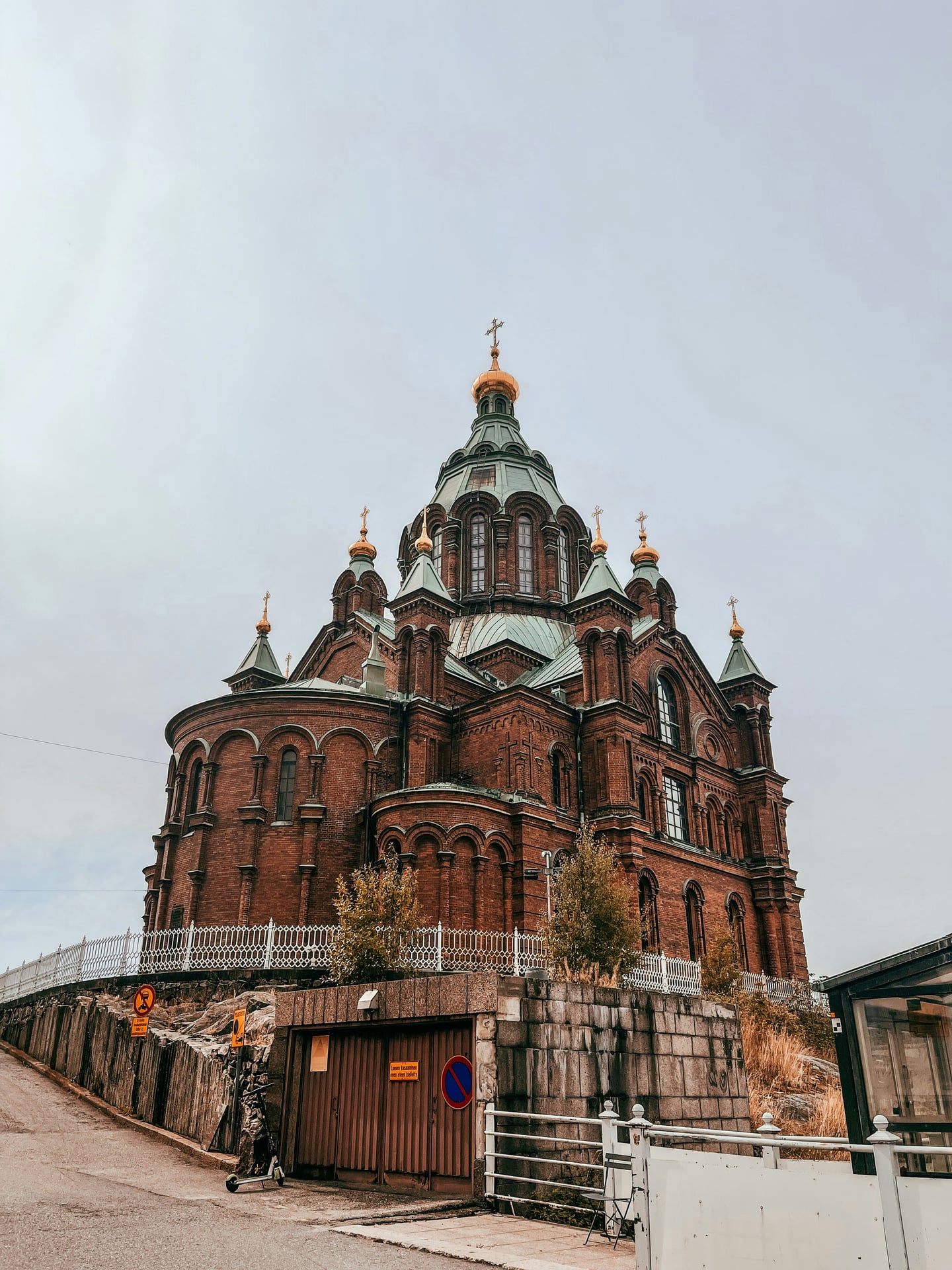 헬싱키 우스펜스키 대성당, 언덕 위로 솟아오른 붉은 벽돌 외벽과 청동 돔 위의 황금 십자가가 조화를 이루는 웅장한 정교회 사원의 전경입니다.