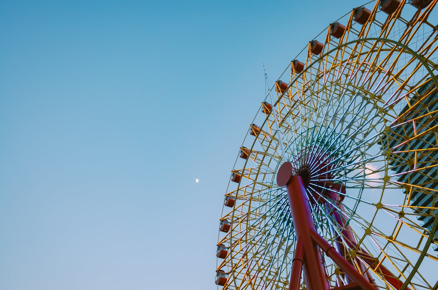 고베 하버랜드 관람차, 푸른 저녁 노을 아래 노란 조명이 켜진 거대한 관람차 바퀴와 붉은 지지대가 어우러진 풍경입니다.