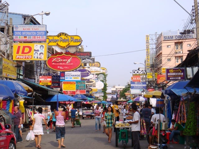 방콕 카오산 로드, 화려한 상점 간판들이 가득한 거리 사이로 많은 관광객들이 활기차게 이동하며 태국 특유의 여행자 거리 분위기를 자아냅니다.