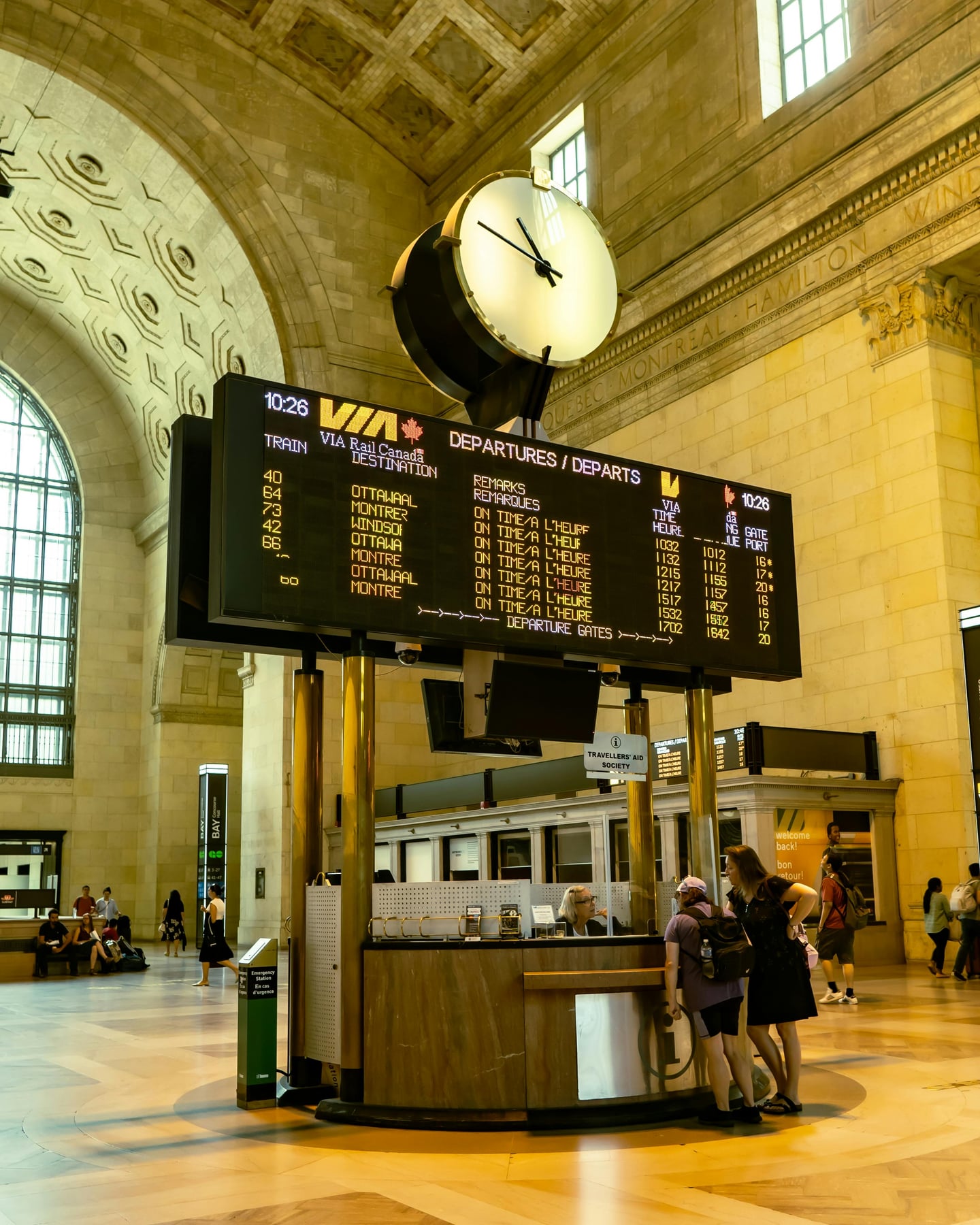 토론토 유니온 스테이션, 웅장한 그레이트 홀 내부의 열차 출발 안내판과 고전적인 대형 시계가 조화를 이루는 풍경입니다.