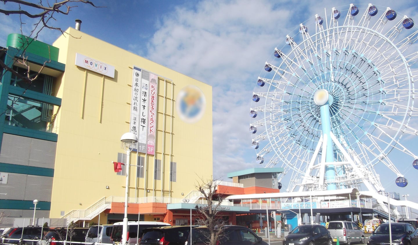 시즈오카 에스펄스 드림플라자, 노란색 쇼핑몰 건물과 푸른 하늘을 배경으로 서 있는 거대한 흰색 대관람차의 모습