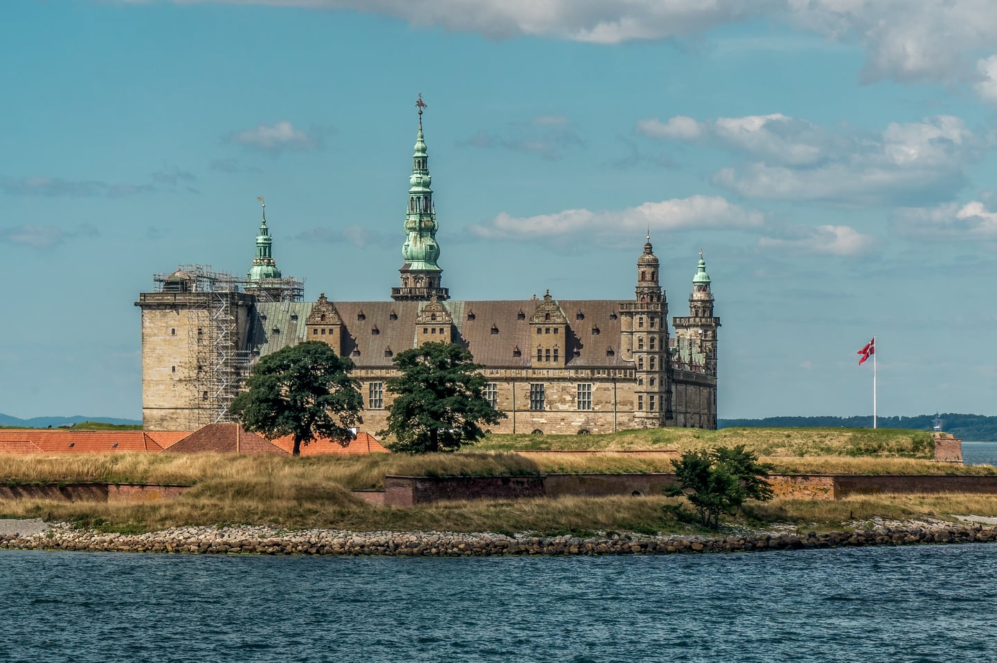 헬싱괴르 크론보르 성, 푸른 바다 너머로 솟아오른 웅장한 르네상스 양식의 성벽과 에메랄드빛 첨탑이 조화를 이룬 풍경입니다.