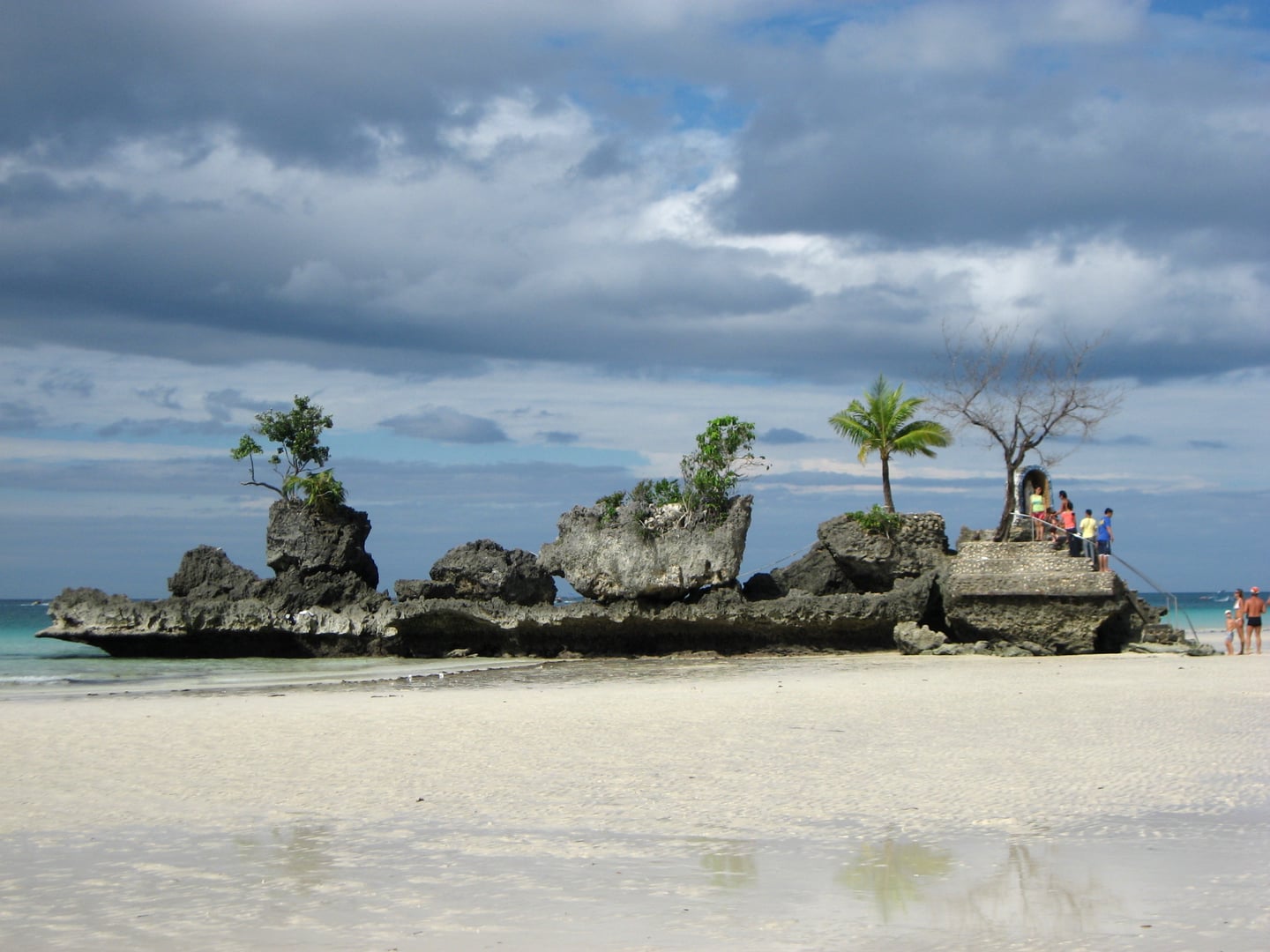 보라카이 윌리스 락, 썰물로 드러난 하얀 백사장 위에 우뚝 솟은 기암괴석과 그 위로 조성된 작은 성모 마리아 사원의 평화로운 풍경입니다.