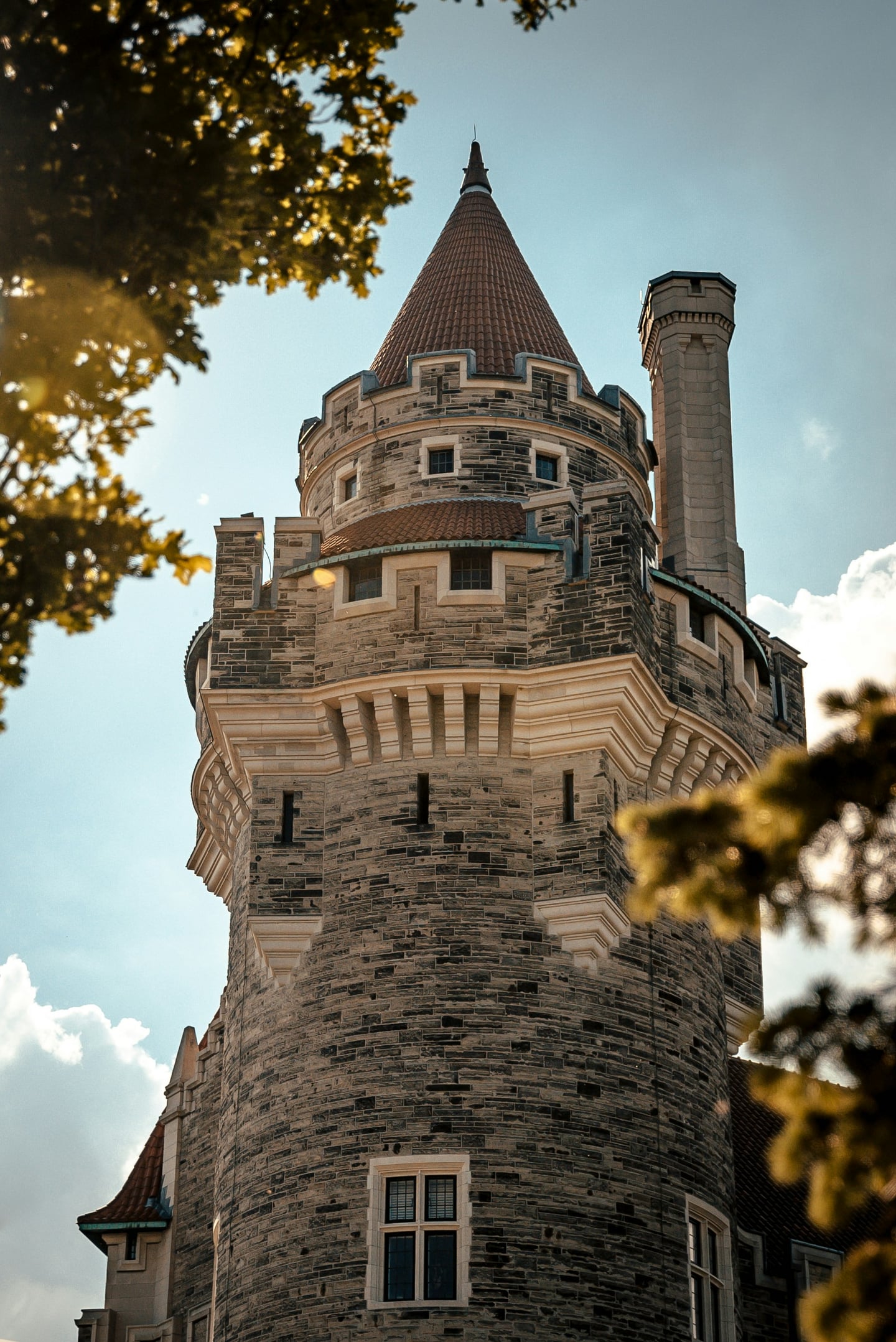 토론토 카사 로마, 푸른 하늘 아래 우뚝 솟은 고풍스러운 석조 타워와 정교한 고딕 양식의 건축미가 돋보이는 성의 외관입니다.