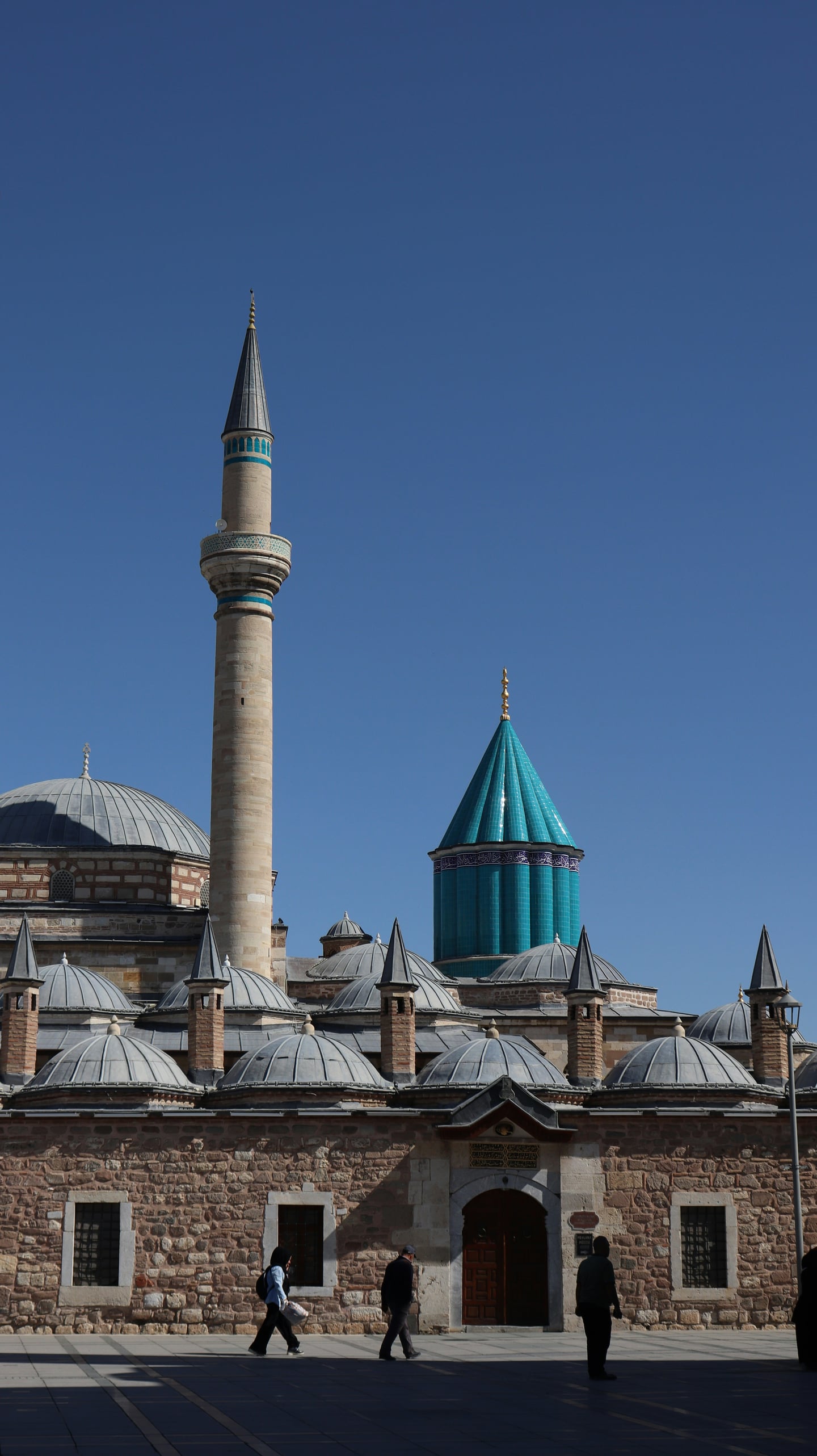 콘야 메블라나 박물관, 맑은 푸른 하늘 아래 우뚝 솟은 상징적인 청록색 돔과 고풍스러운 석조 건축물의 조화로운 풍경.