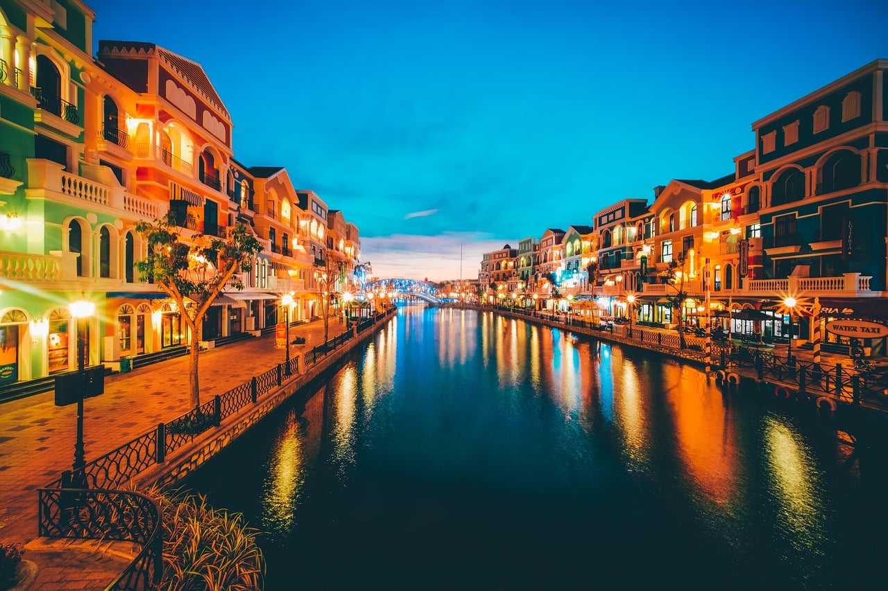 푸꾸옥 빈 그랜드 월드, 화려한 조명이 켜진 유럽풍 건물들과 운하가 어우러진 환상적인 야경 풍경입니다.