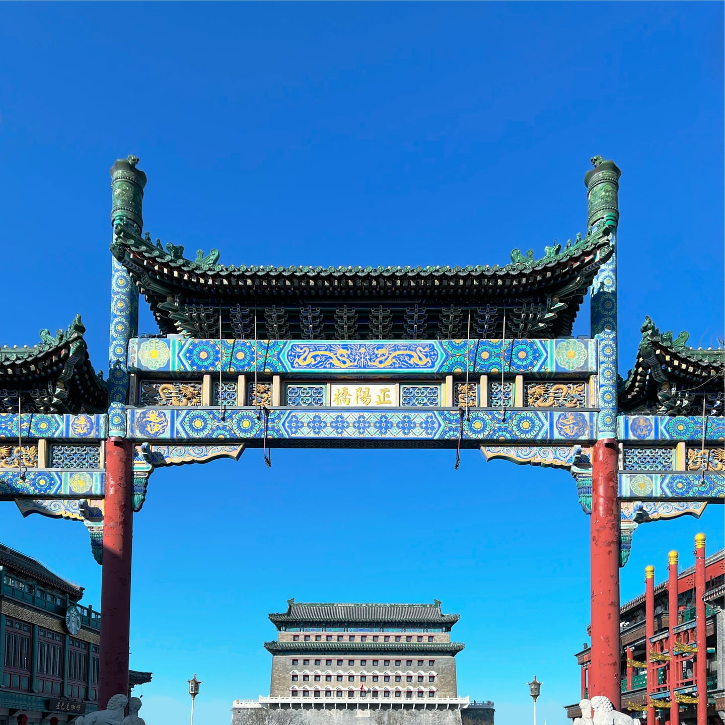 베이징 전문대가, 화려한 푸른색 문양의 전통 패루 너머로 웅장하게 솟아 있는 정양문 화살탑과 맑은 가을 하늘의 풍경입니다.