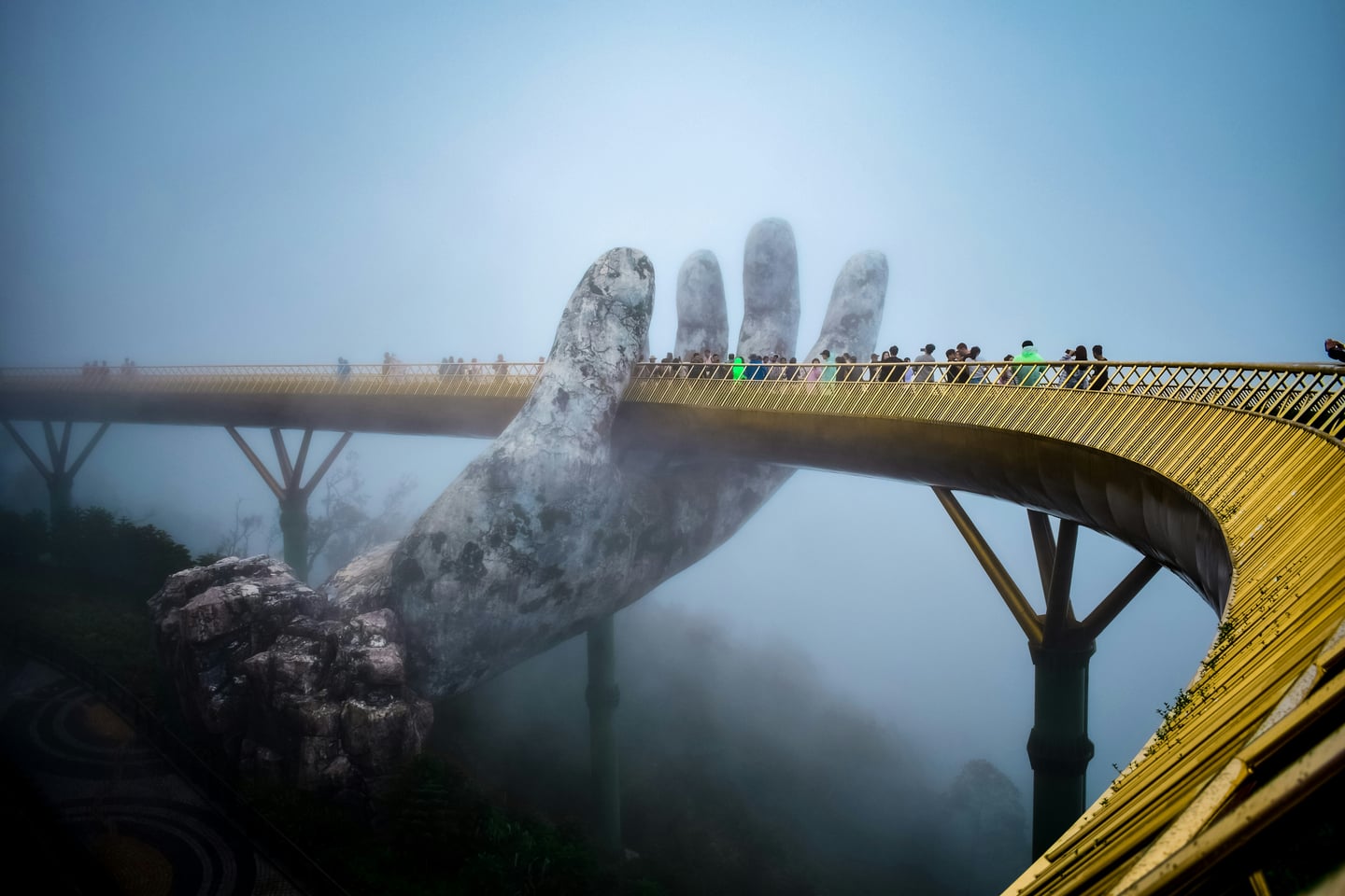 다낭 바나힐, 안개 속에서 거대한 신의 손이 황금빛 다리를 받치고 있는 신비로운 골든 브릿지의 전경입니다.