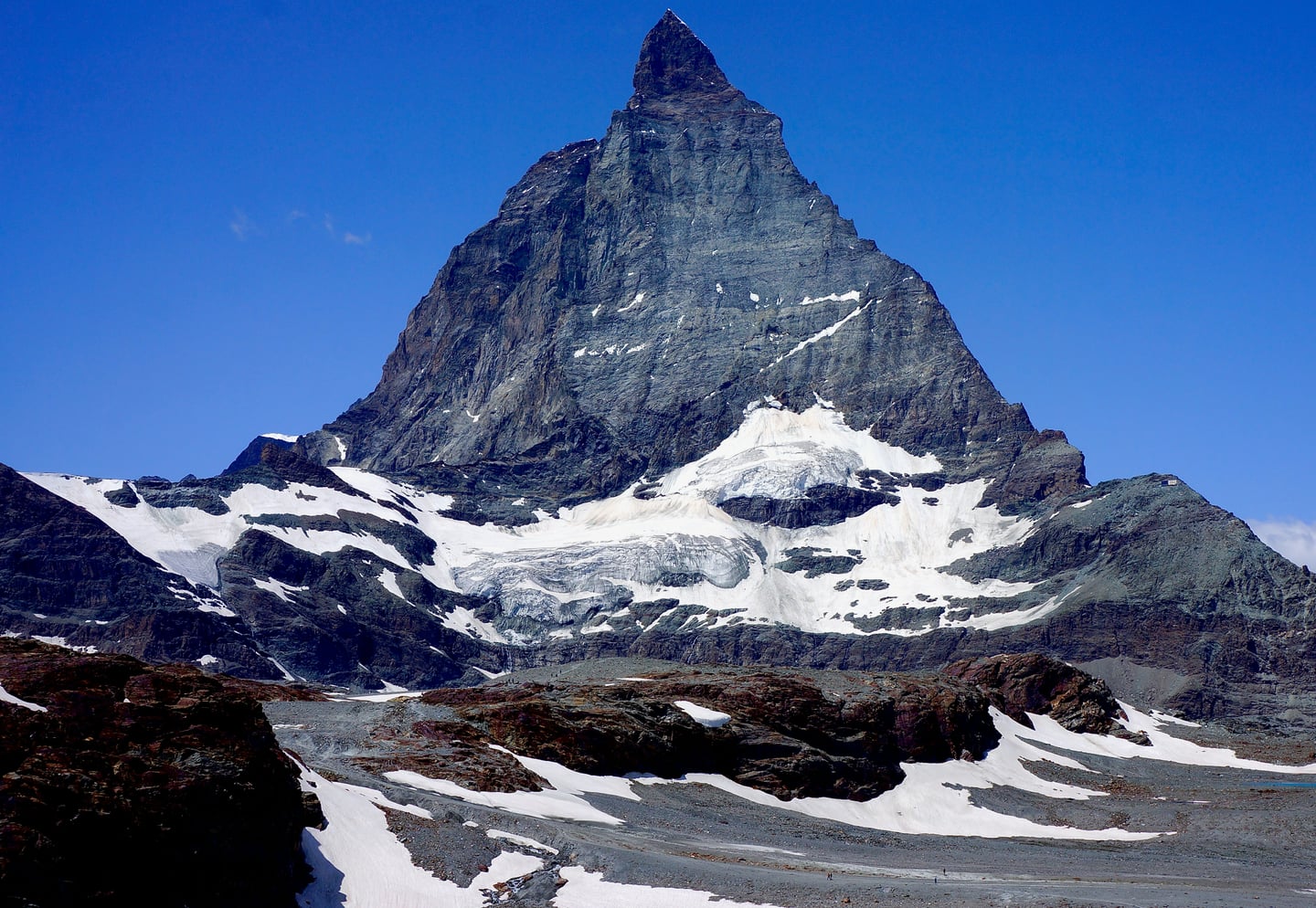 체르마트 마테호른, 맑고 푸른 하늘을 배경으로 날카로운 피라미드 형태의 암벽과 잔설이 어우러진 웅장한 산봉우리의 전경입니다.