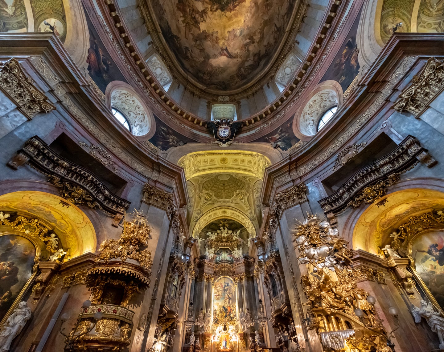 빈 페터 교회, 화려한 금빛 장식과 정교한 돔 프레스코화가 어우러진 웅장한 바로크 양식의 성당 내부 전경입니다.