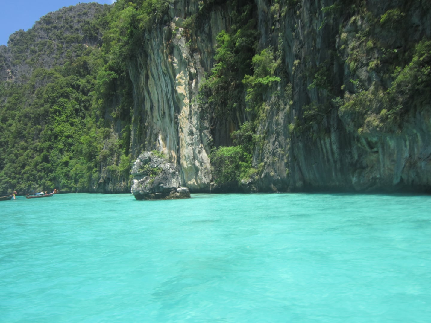 푸켓 피피섬, 에메랄드빛 투명한 바다와 웅장한 석회암 절벽이 어우러져 신비롭고 평화로운 열대 낙원의 풍경을 보여줍니다.