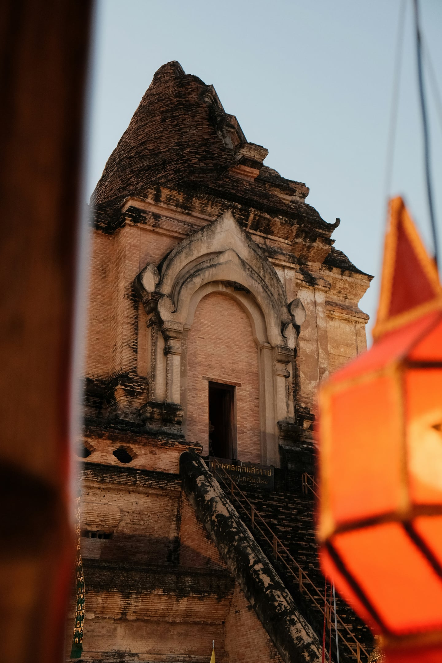 치앙마이 왓 체디 루앙, 붉은색 전통 등 너머로 보이는 고대 벽돌 불탑의 웅장한 아치형 입구와 세월이 깃든 건축미.