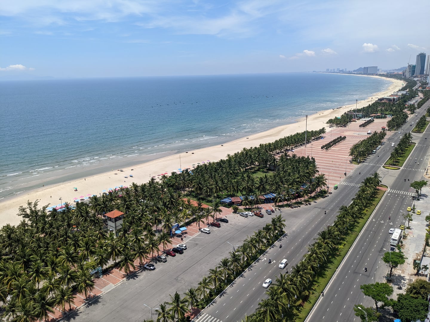 다낭 미케비치, 끝없이 펼쳐진 푸른 해안선과 야자수가 늘어선 해변 도로가 어우러진 시원한 전경입니다.