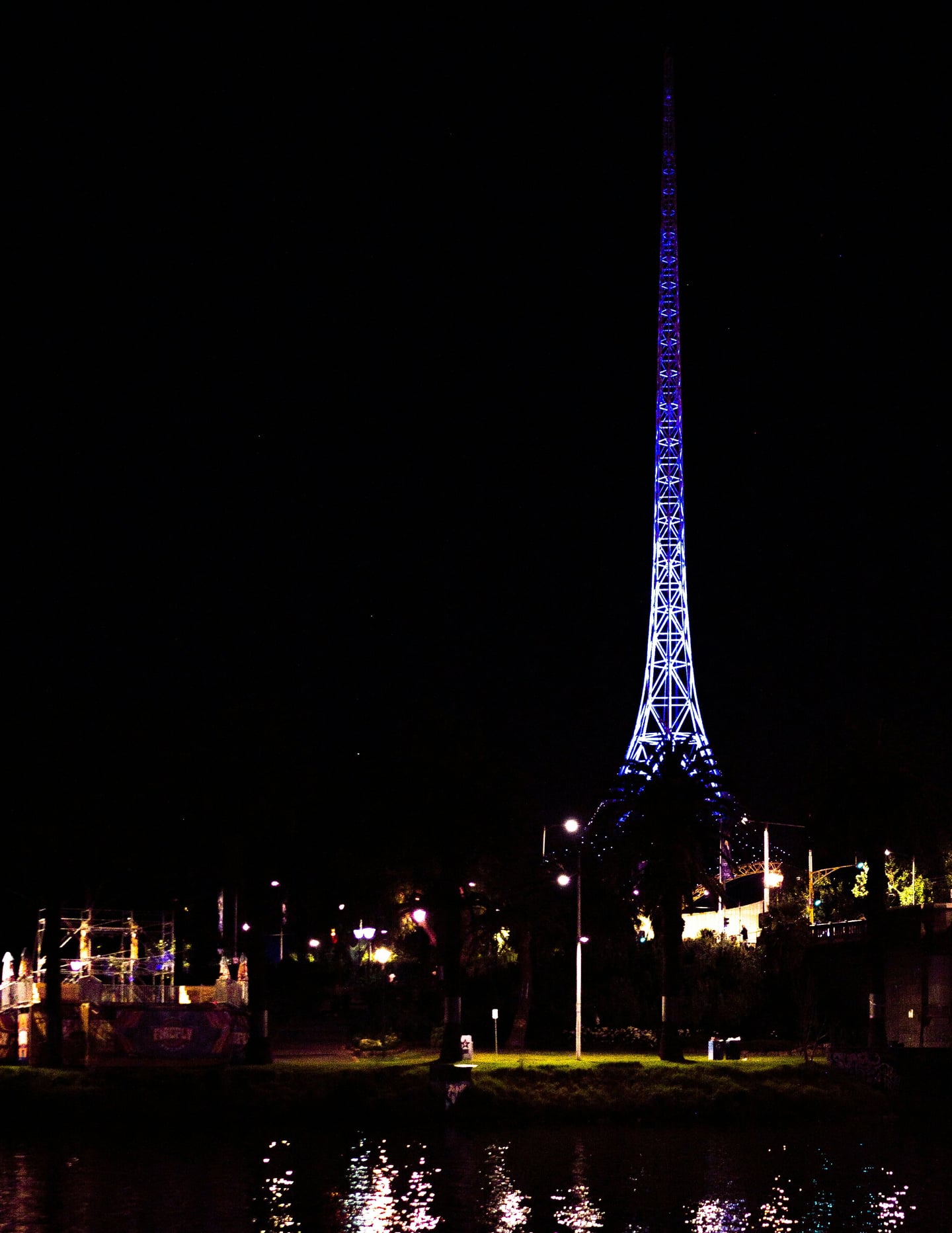 멜버른 빅토리아 아트 센터, 칠흑 같은 밤하늘 아래 푸른 빛으로 화려하게 빛나는 예술 센터의 상징적인 첨탑 야경입니다.