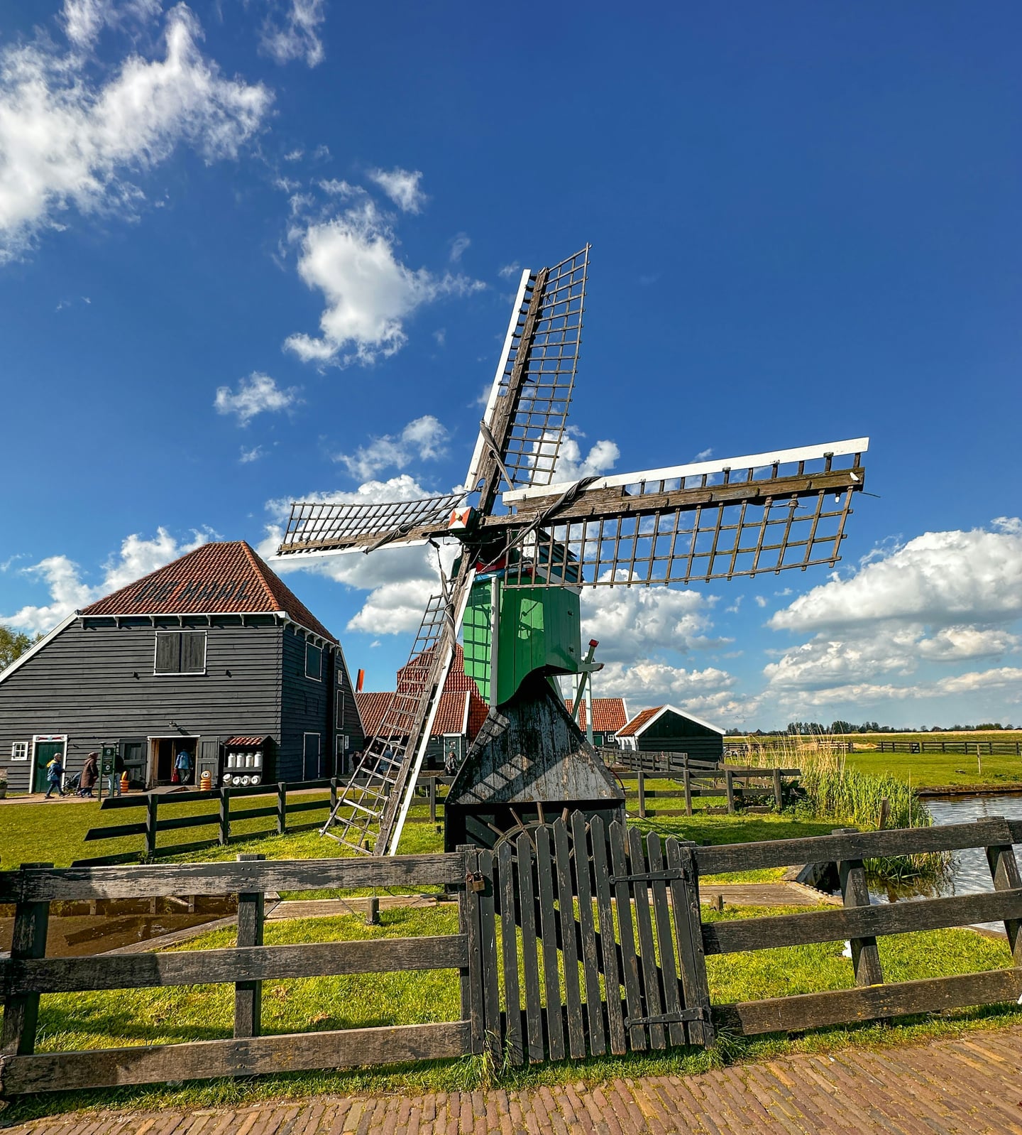 암스테르담 잔세스칸스 풍차마을, 맑은 하늘 아래 우뚝 솟은 전통 풍차와 고즈넉한 목조 가옥이 어우러진 평화로운 전원 풍경입니다.