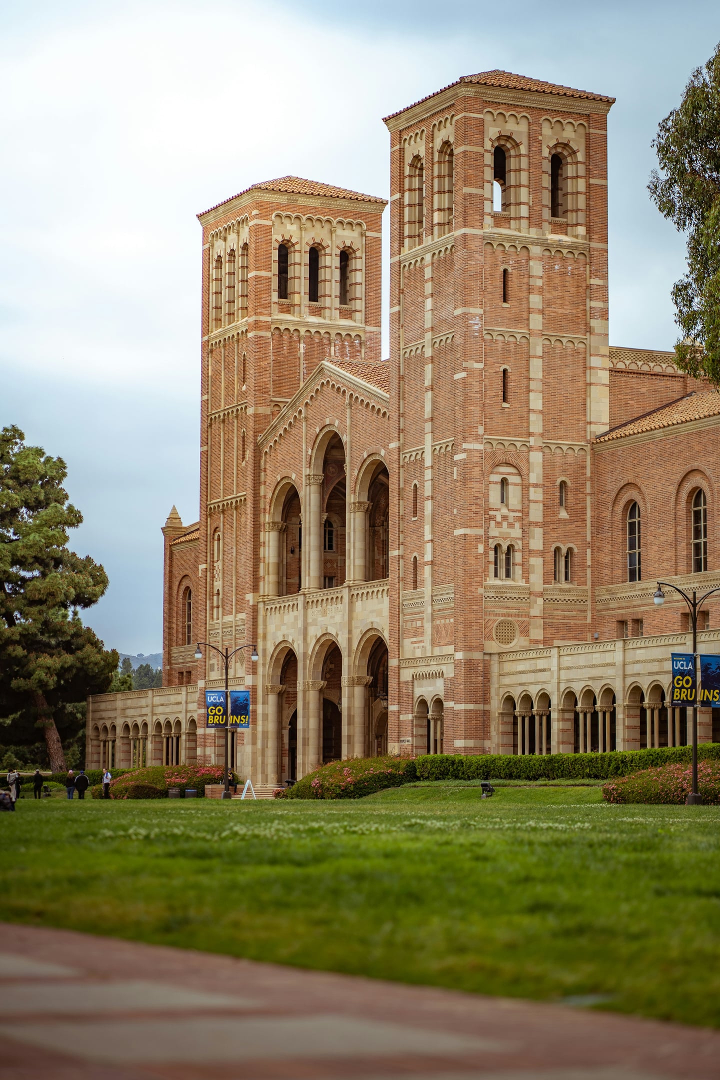 로스앤젤레스 UCLA, 로마네스크 양식의 웅장한 로이스 홀 건물과 푸른 잔디밭이 어우러진 캠퍼스의 평화로운 풍경입니다.