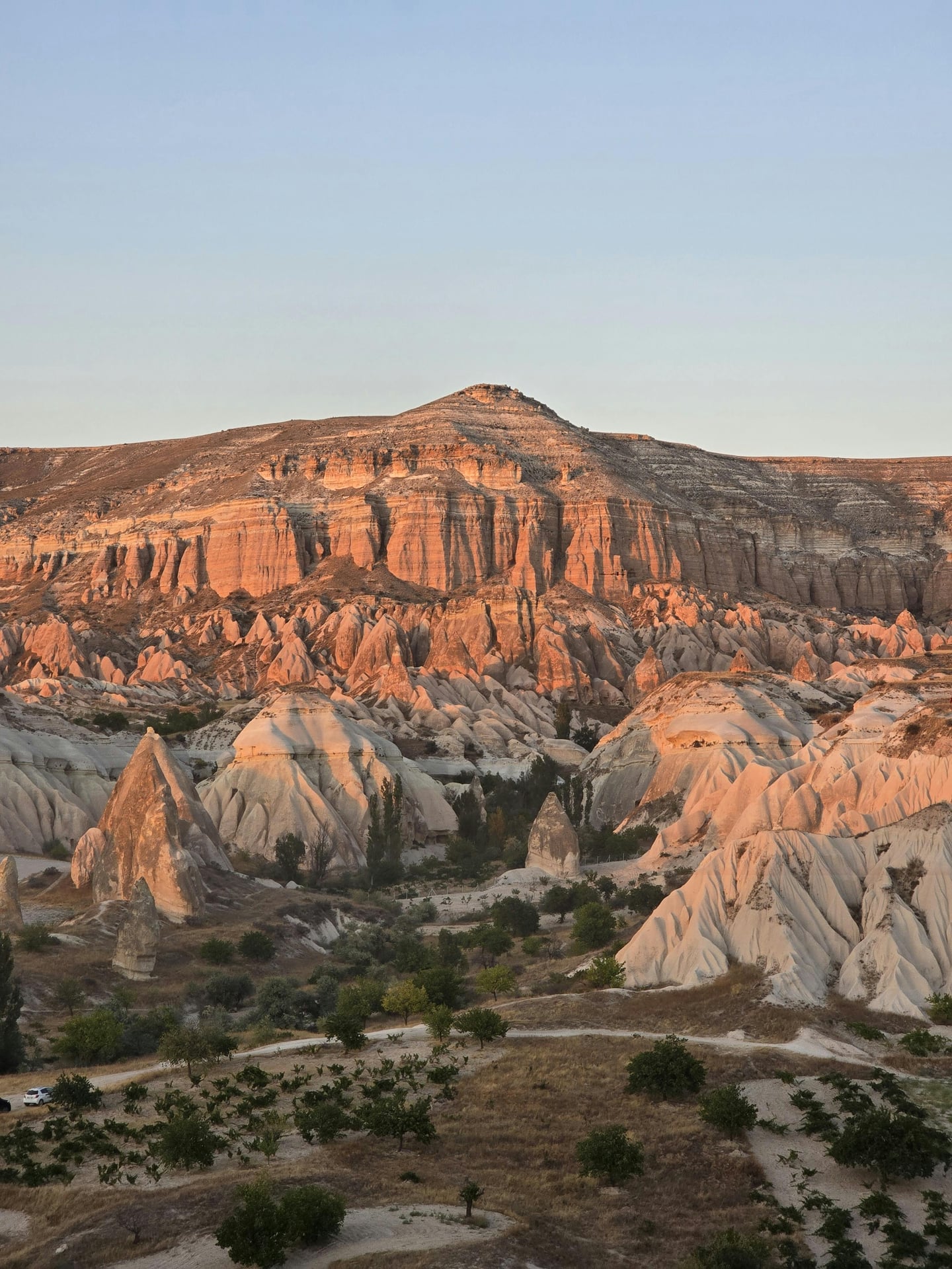 카파도키아 로즈밸리, 석양의 붉은 빛이 감도는 기암괴석 절벽과 원뿔형 바위들이 어우러진 신비로운 계곡 풍경입니다.